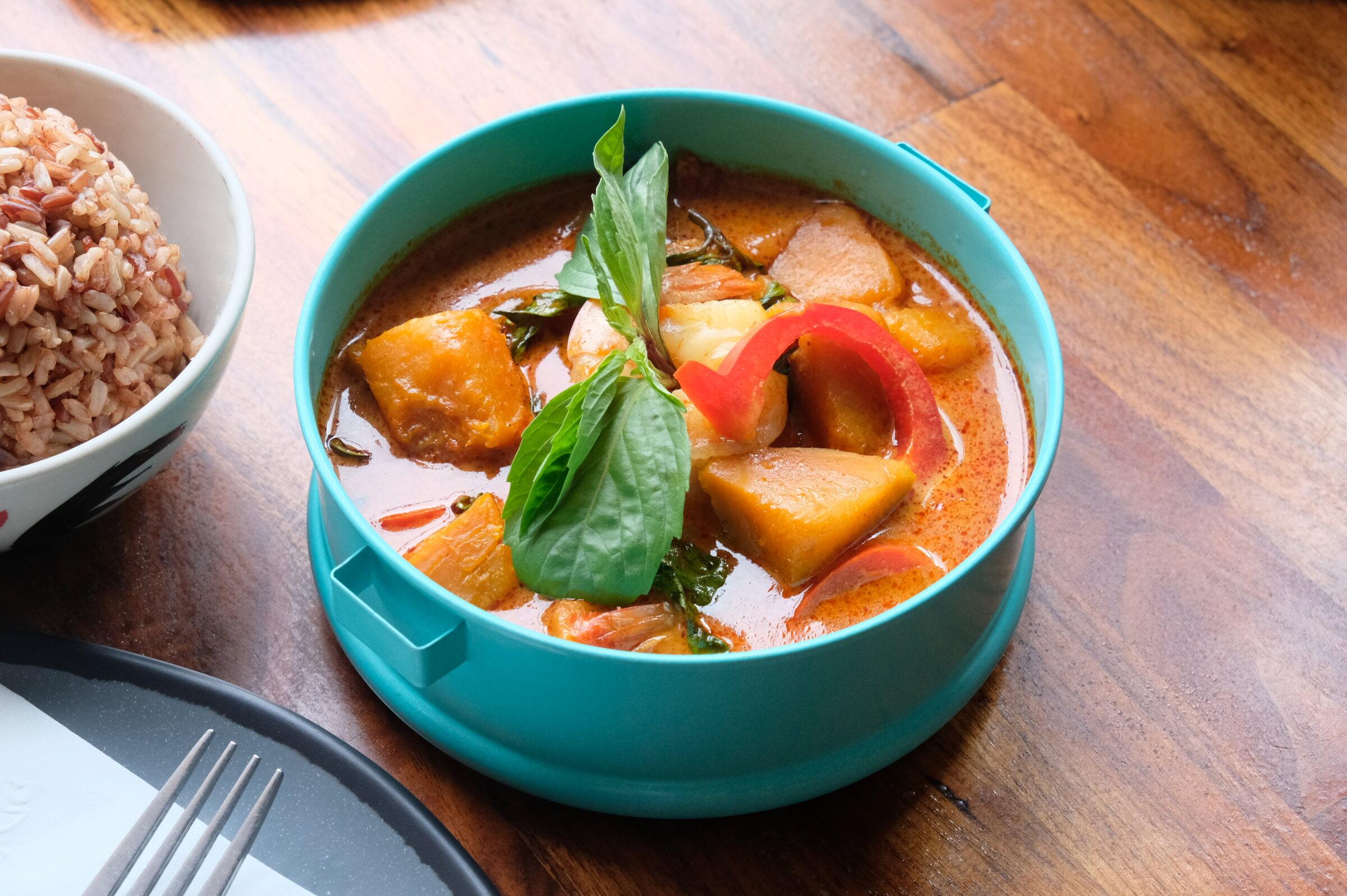 Red curry with pumpkin, bell pepper and basil in a turquoise bowl, served with brown rice.